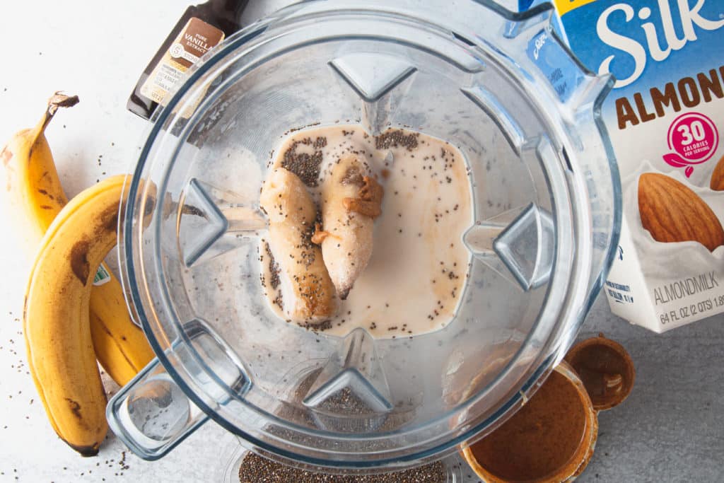 banana chia seeds almond butter smoothie in glass jar with metal straw